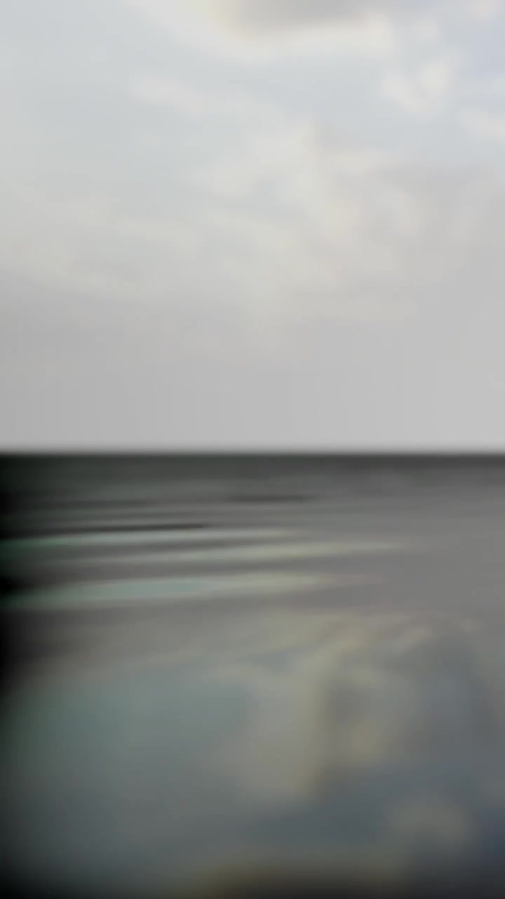 Wide view of a calm water surface with light reflections at sunset