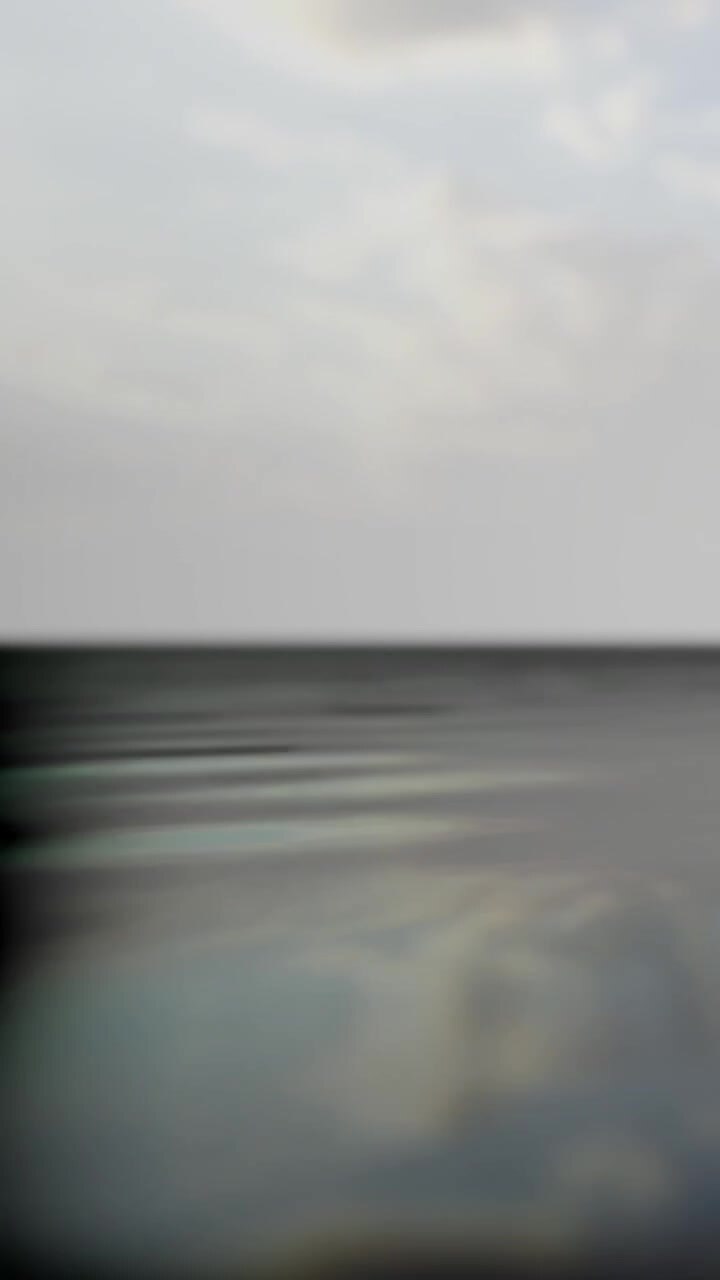 Wide view of a calm water surface with light reflections at sunset