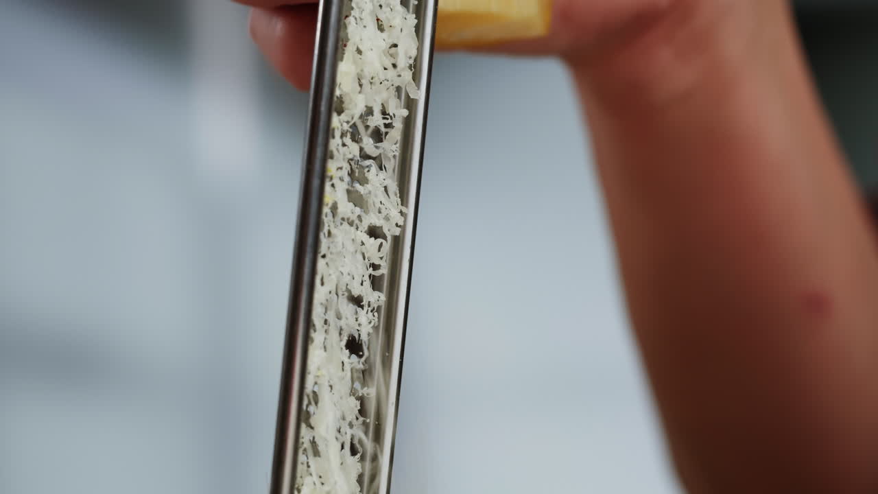 Close-up of Hand Grating Cheese with a Metal Grater