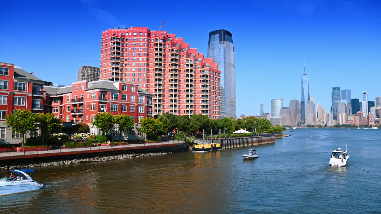 Jersey City, Hoa Kỳ, ngày 1 tháng 7 năm 2025: Các tòa nhà dân cư bằng gạch đỏ trên bờ sông Jersey City. Khung cảnh tuyệt đẹp của các tòa nhà dân cư bằng gạch đỏ dọc theo bờ sông Jersey City với những chiếc thuyền trên sông Hudson và các tòa nhà chọc trời ở phía xa