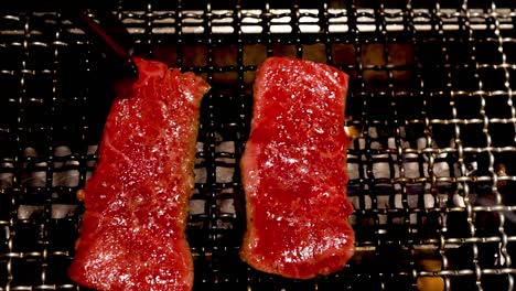 two steaks sizzling on a grill, with tongs flipping them for even cooking.