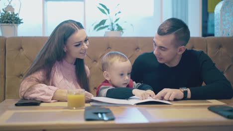 la familia se sienta en una mesa de madera marrón y se comunica
