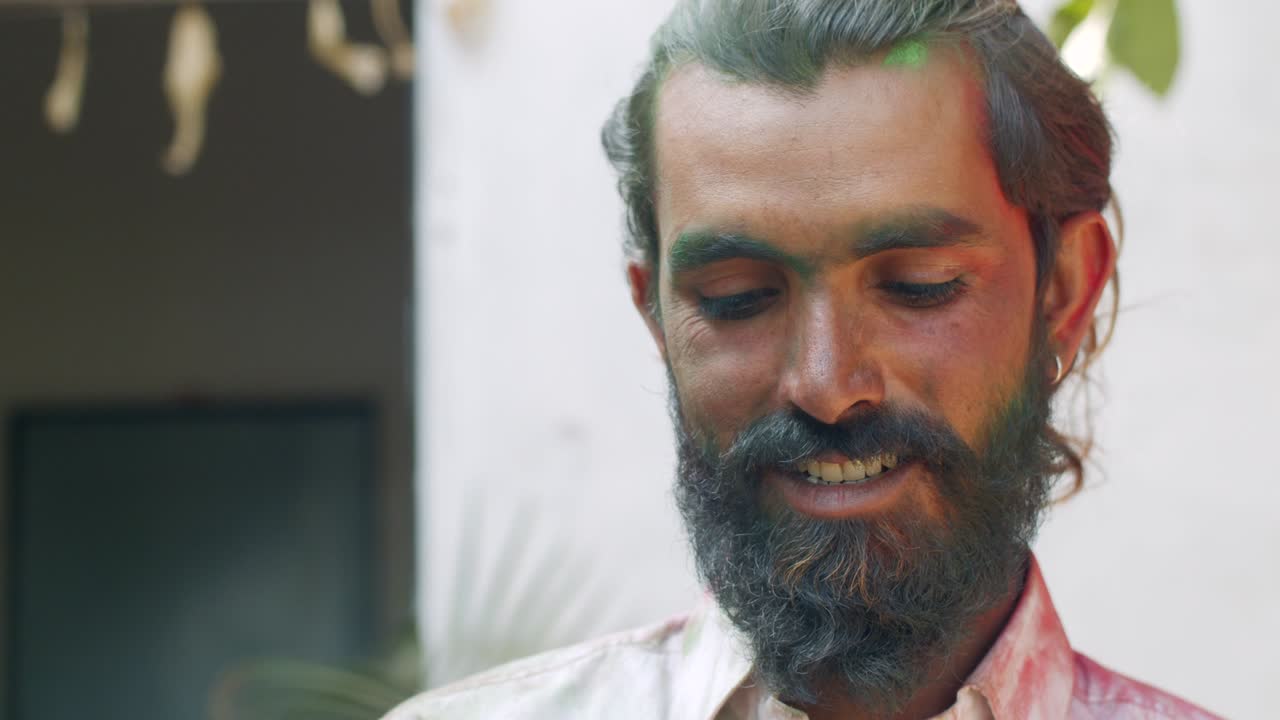 Indian man close-up of face smeared with bright Holi colors