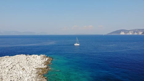 Boats-Navigating-the-Oceans-Between-The-Rocky-Shores-And-Mountain-Of-Paralia-Emplisi,-Kefalonia-In-Greece--Aerial-Shot