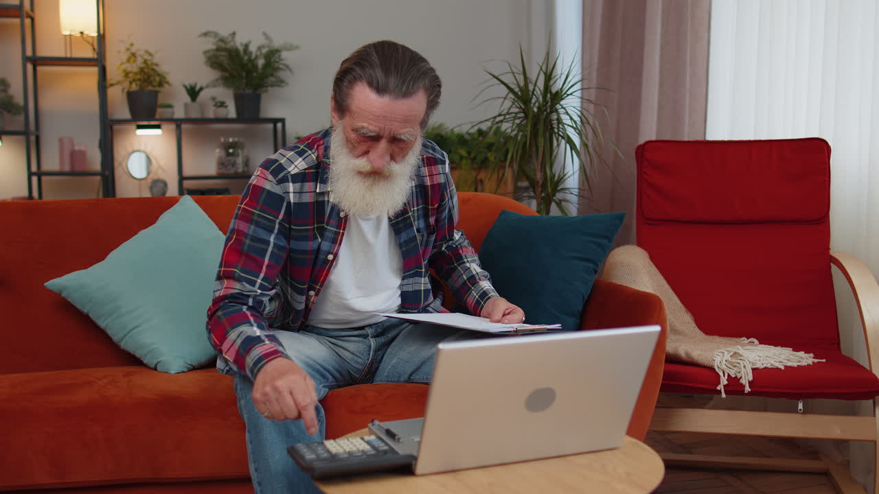 Senior man accounting payments calculating monthly expenses bank bills, analysing paperwork at home