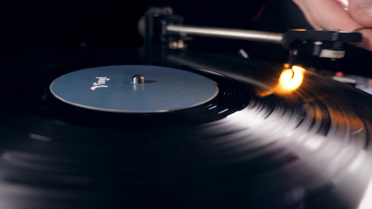 한 사람 이 비닐 디스크 를 가지고 레코드 플레이어 를 발사 하고 있다