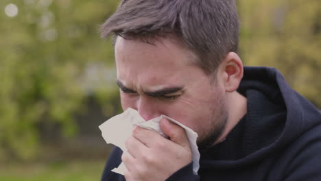 sick man at park coughing in a handkerchief