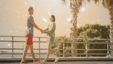 Animación-De-Focos-Sobre-Una-Feliz-Pareja-Diversa-Tomados-De-La-Mano-Caminando-Junto-Al-Mar