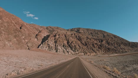 driving-through-the-dry-desert-by-mountains