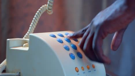 african american hand picking up receiver of a analog phone and dialing