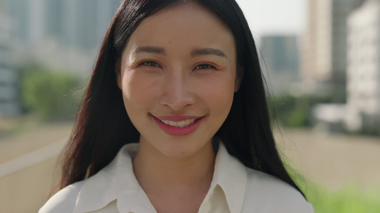 Close-up portrait of a young Asian woman smiling outdoors