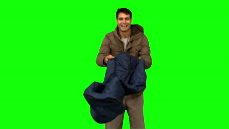 Cheerful-man-rolling-out-his-sleeping-bag-on-green-screen