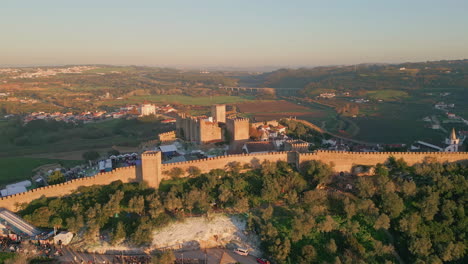 aerial medieval fortress stretching at nature greenery at evening light.