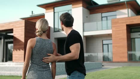 handsome man closing woman eyes near house. surprised woman standing near villa