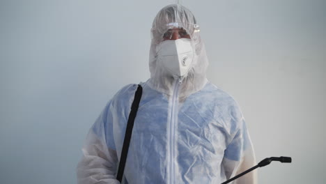 person in protective suit with sprayer