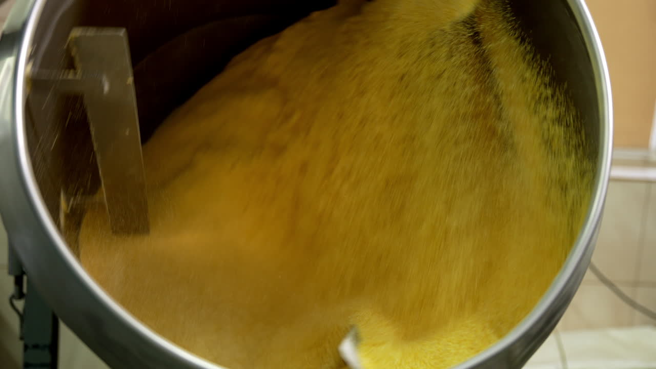 Centrifuge mechanism rotating and mixing yellow stuff. Maize snacks production at food factory. Close up.