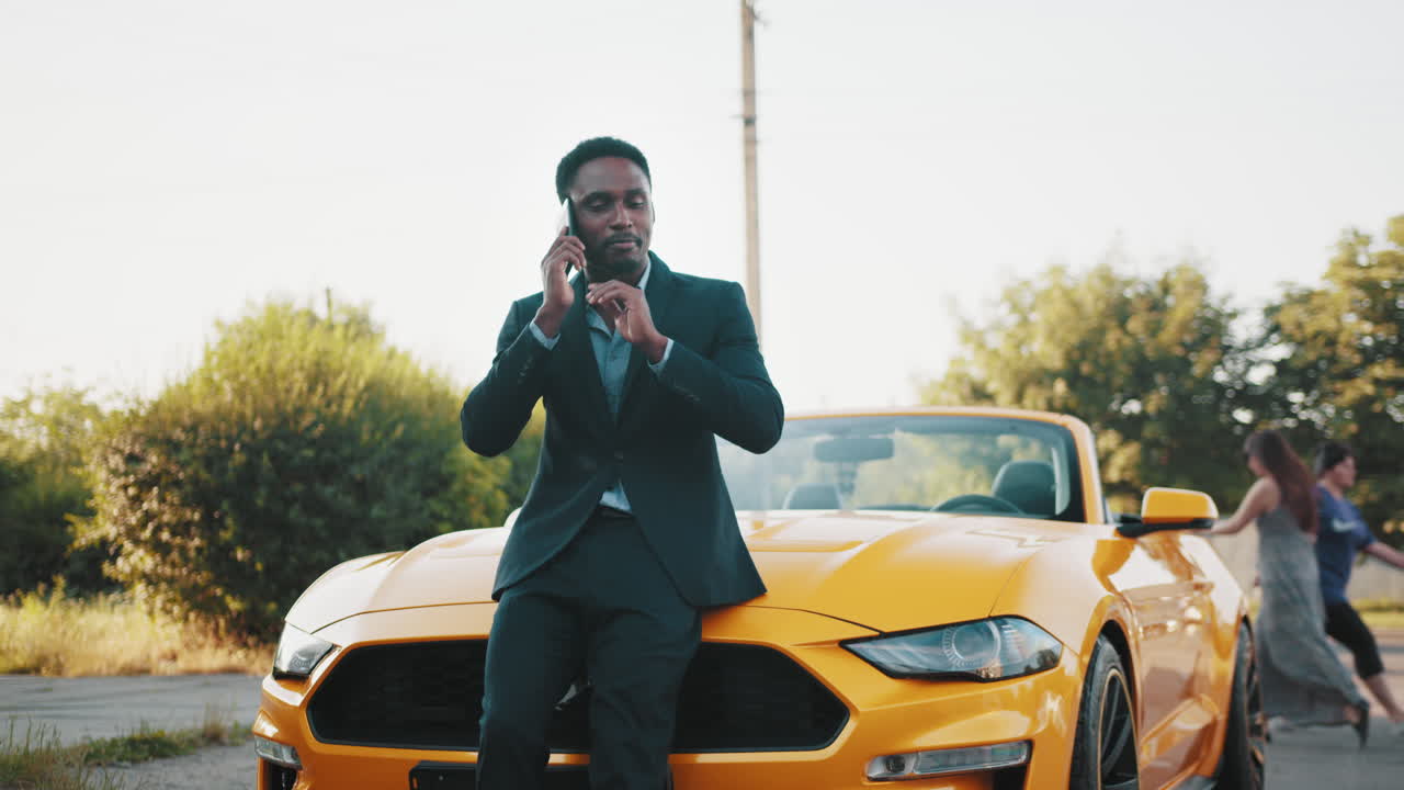 hombre de negocios en el teléfono cerca del descapotable amarillo