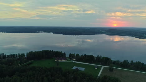 Lago-Tranquilo-Y-Reflectante-Al-Atardecer-Con-Una-Plataforma-Rodante-Aérea-Cinematográfica-A-La-Izquierda