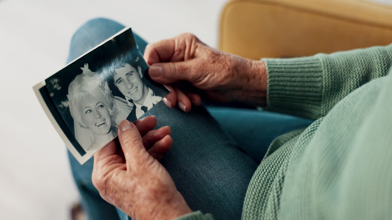 Hands, photograph and memory on a home sofa