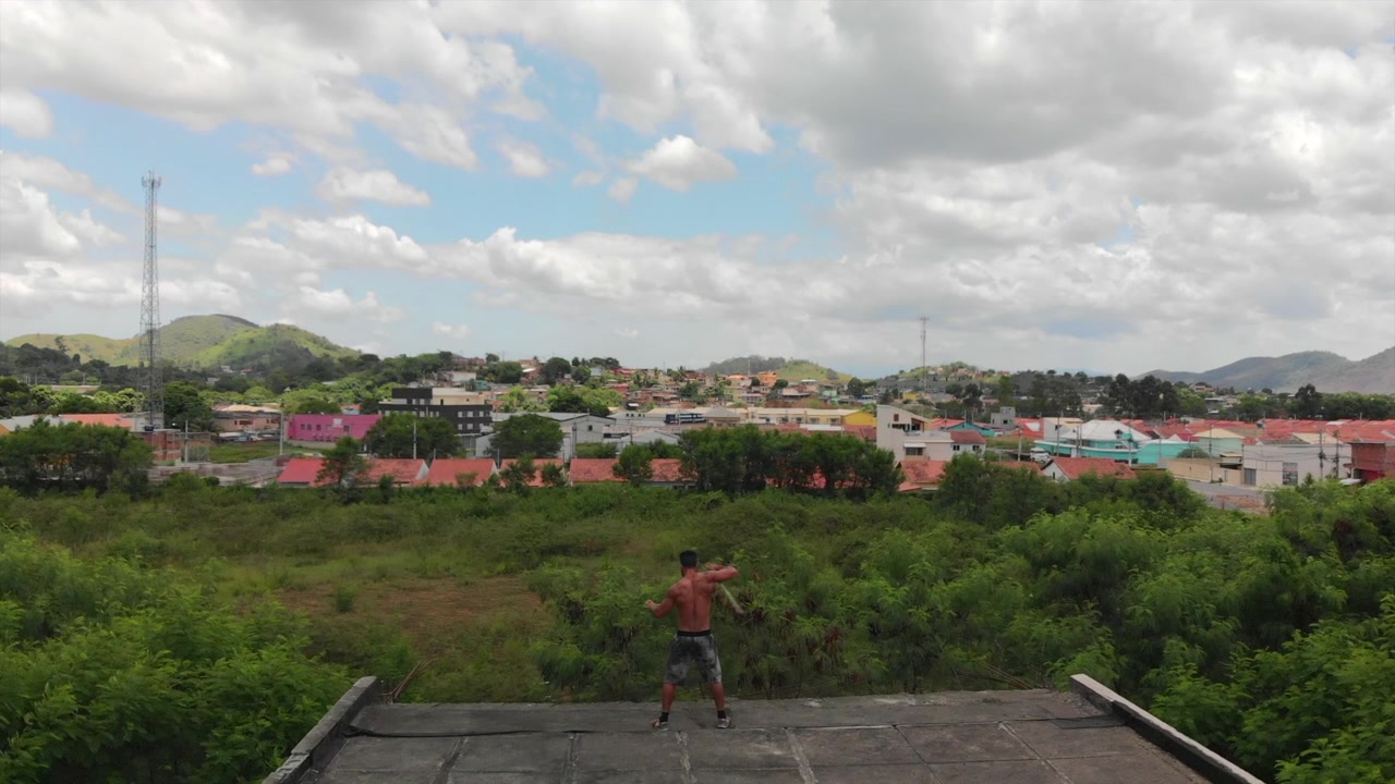 Vídeo de Drone de um Homem Fazendo Truques de Artes Marciais com um Bastão em um Telhado