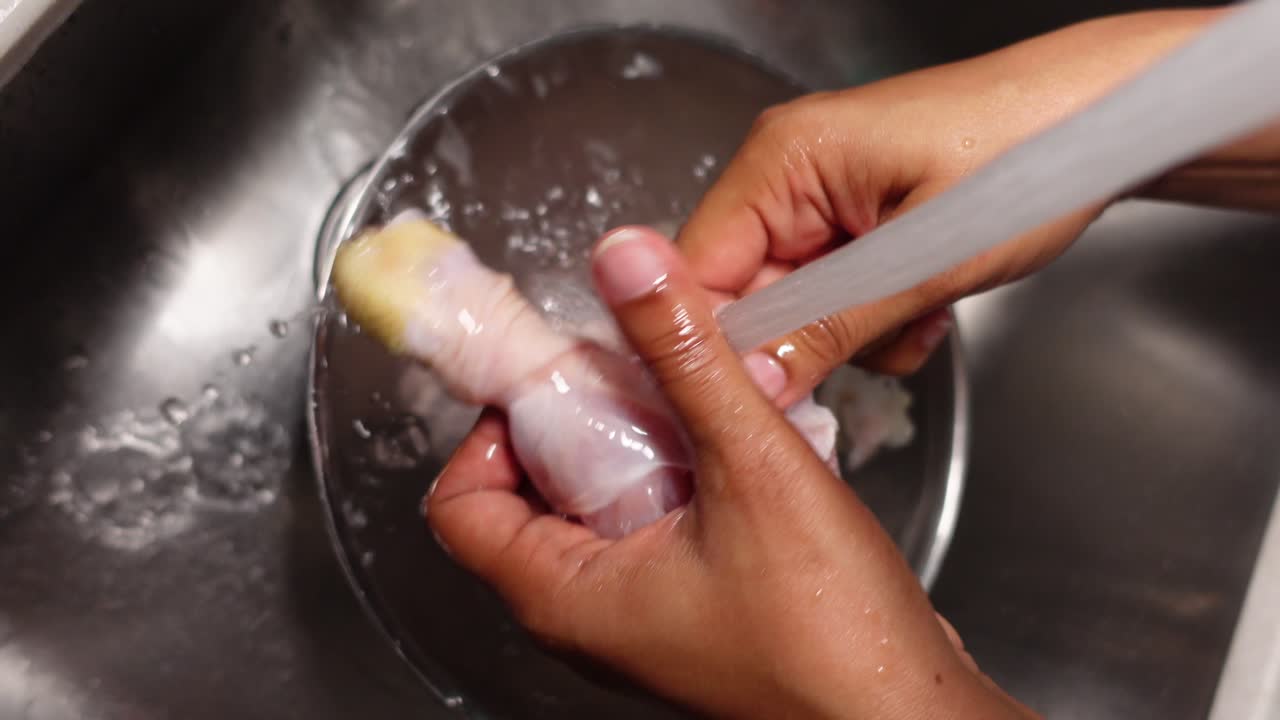 Washing raw chicken drumsticks in a sink