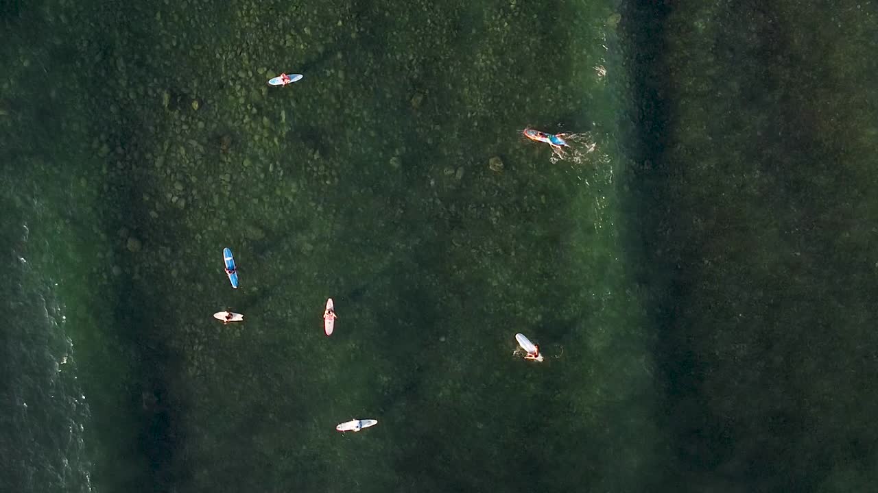 멕시코 사율리타의 얕은 바위 바닥 만에서 파도를 기다리는 서퍼들의 하향식 공중