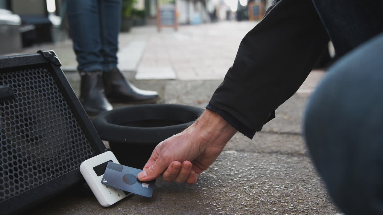 Close Up Of Contactless Payment Machine At Feet Of Female Musician Busking In Street