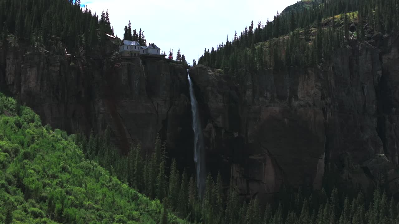 Stunning Waterfall cascading down a cliffside near a house in the mountains
