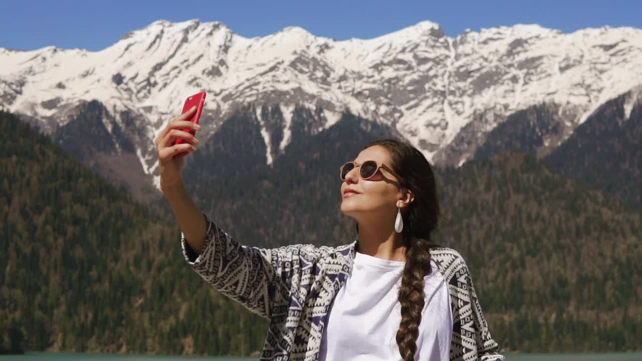 mujer tomando una selfie frente a montañas nevadas