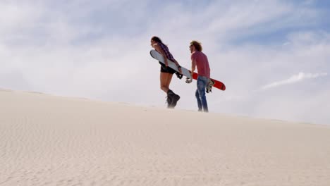 Couple-walking-with-sand-boards-in-the-desert-4k