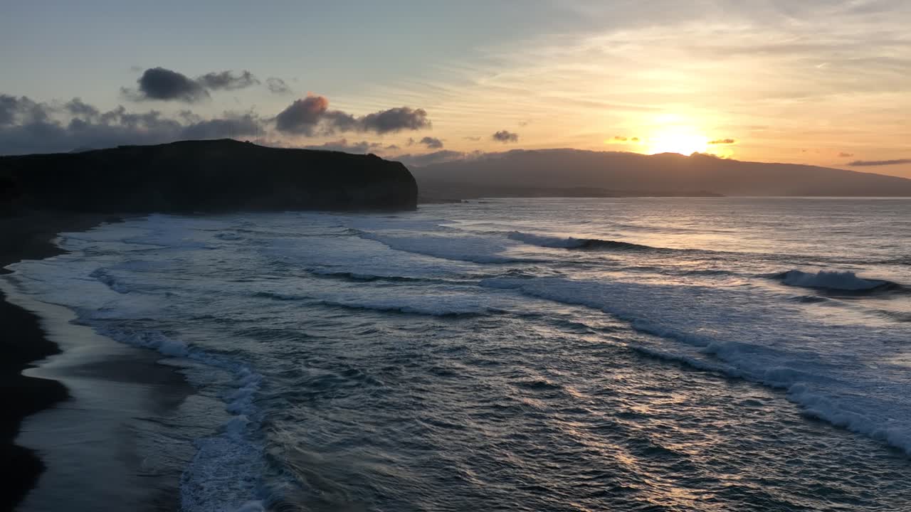 Cinematic slomo aerial at sunset over coastline as waves roll in, Santa Barbara