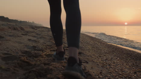 Closeup-slim-woman-feet-walking-sandy-beach-at-sunset.-Girl-steping-on-seacoast