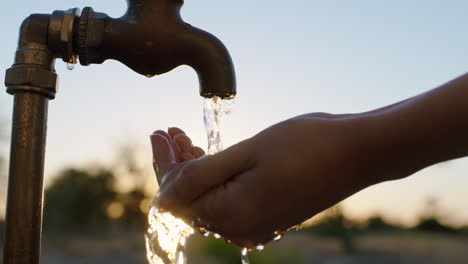 Frauenhände-Fangen-Wasser-Unter-Leitungswasser-Auf-Durstiger-Bauer-Trinkt-Süßwasser,-Das-Bei-Sonnenuntergang-Aus-Dem-Wasserhahn-Fließt,-Spart-Wasserkonzept