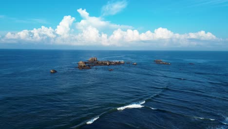 Aerial-drone-landscape-view-of-rocky-ocean-point-break-headland-with-clouds-in-sky-horizon-background-Turtle-Beach-diving-Hikkaduwa-Sri-Lanka-Asia