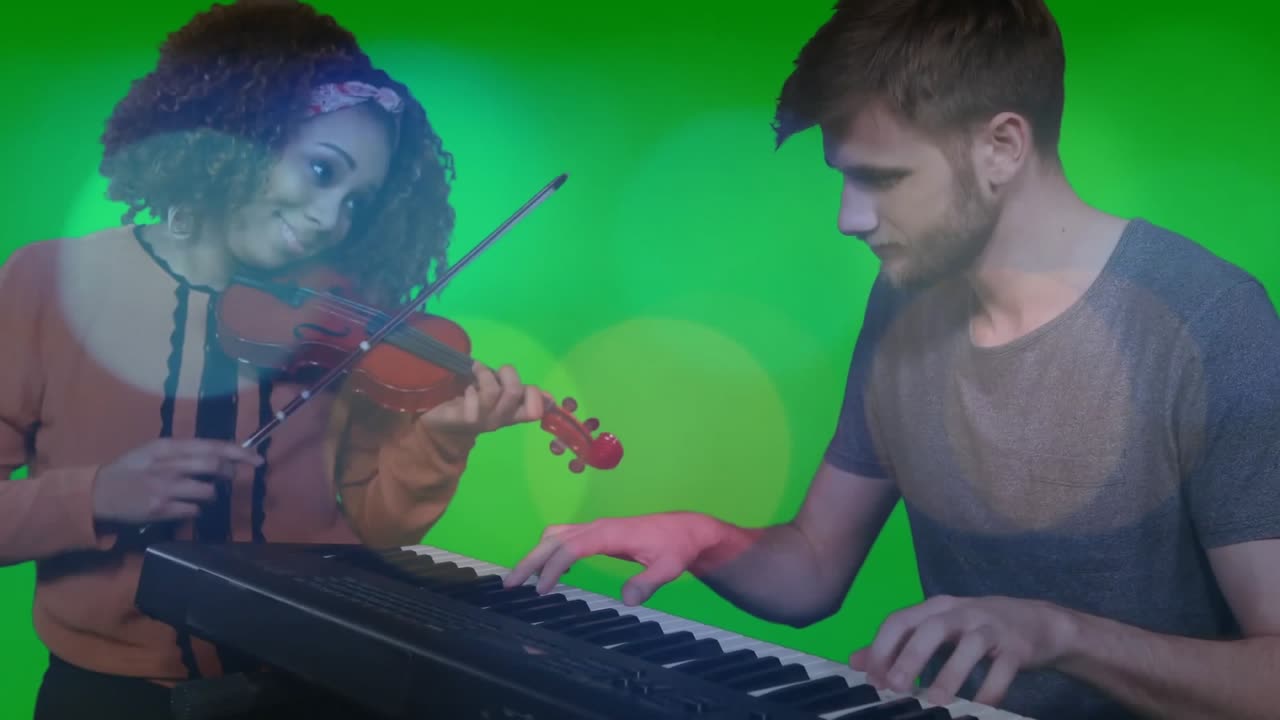 Donna che solleva un violino rosso e uomo che preme i tasti della tastiera su green screen, sincronizzando il ritmo della musica.