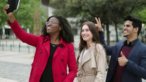 Three-young-people-standing-one-by-one,-making-selfie-on-tablet