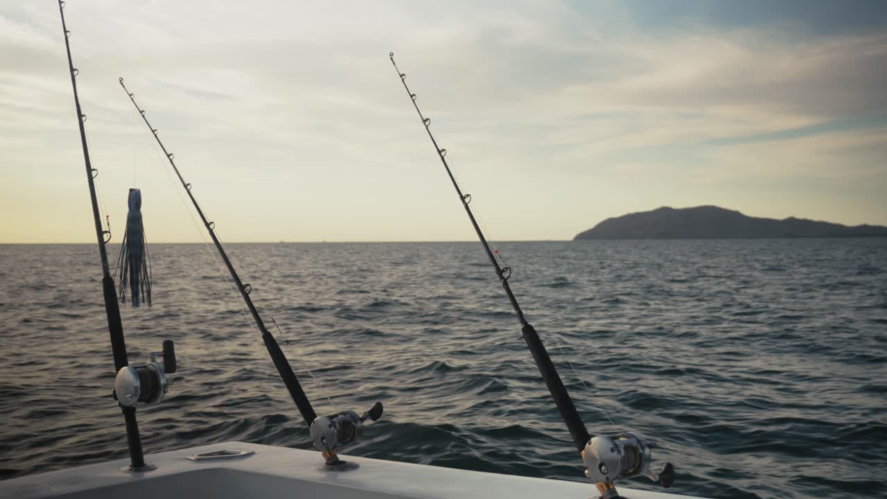Camera fixed on three fishing rods mounted on a boat as they point toward the open sea.