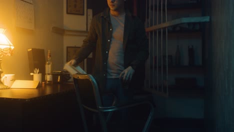 man sits alone in his apartment, drinks and thinks.
