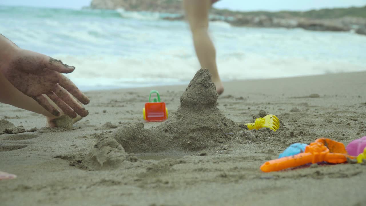 엄마와 어린 소녀가 모래 성을 만들고 모래 탑을 만들고