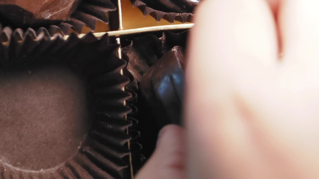 Hand picking chocolate from a box