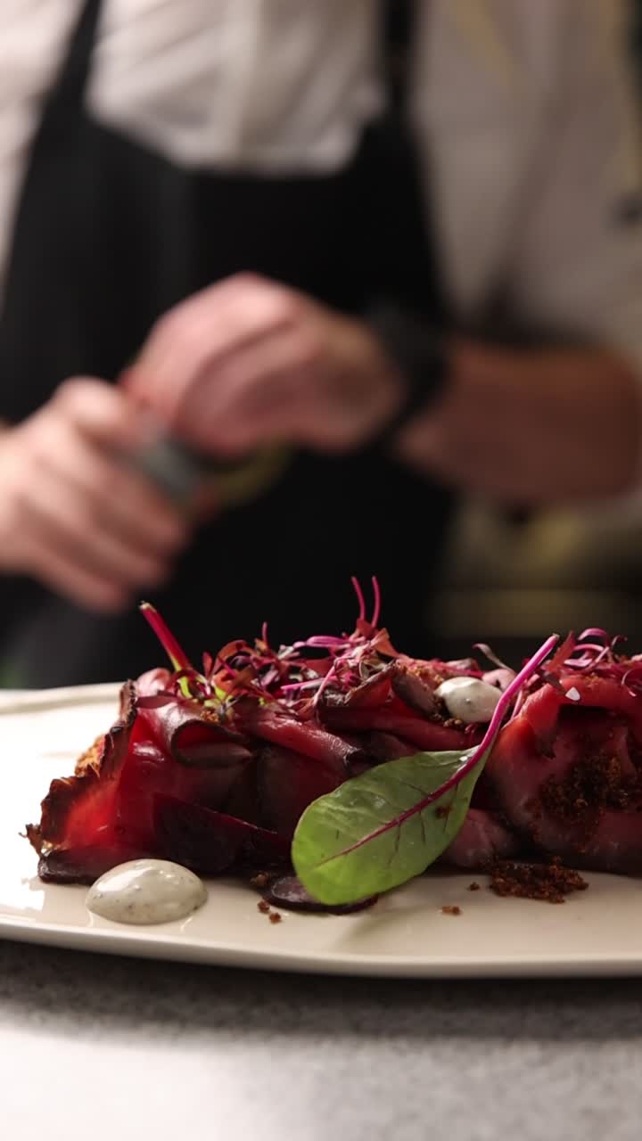 Kokki valmistanut gourmet-annos ohuiksi viipaloitua lihaa ja koristeita