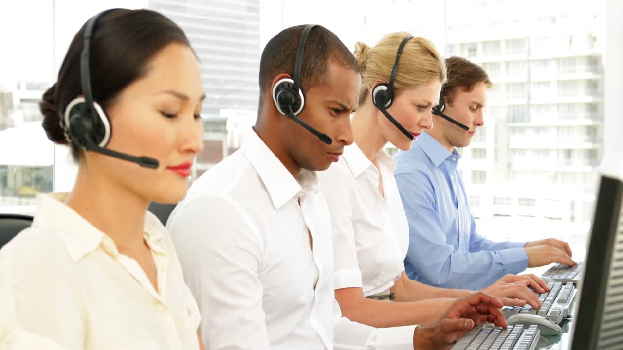 Call centre agents working with one smiling at camera