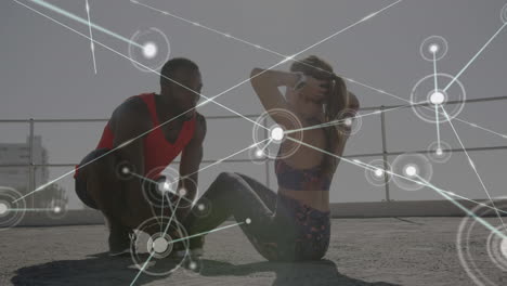 network of connections against biracial couple performing abs exercise together on the promenade