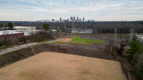 vuelo aéreo hacia adelante sobre el campo cerca de la red de energía eléctrica y el horizonte de la ciudad de atlanta en el fondo