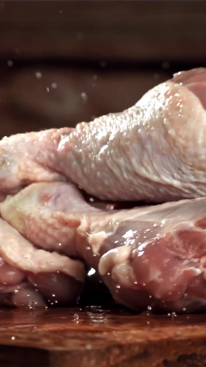 Fusi di pollo freschi e crudi che cadono su una superficie di legno rustica