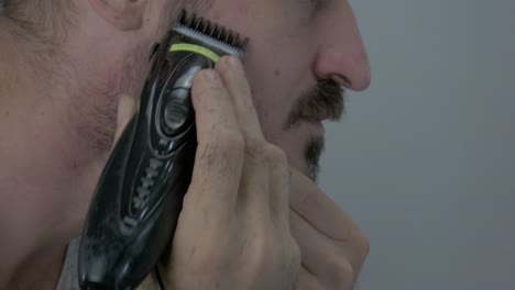 a man is trimming his facial hair with an electric razor to look good