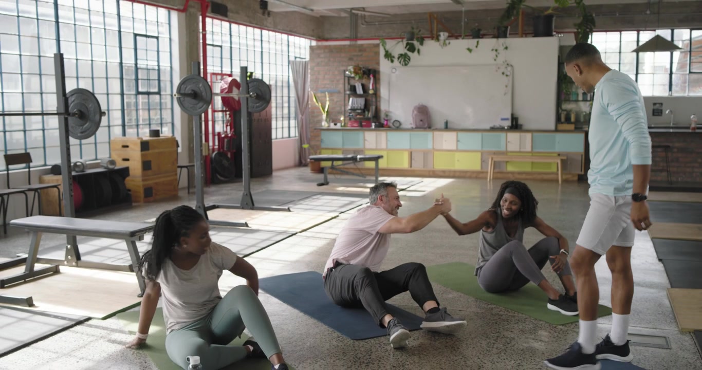 Geführter Fitnesskurs: Teilnehmer folgen den Anweisungen des Trainers und machen Crunches auf Matten in einem Loft für die Rumpfmuskulatur.