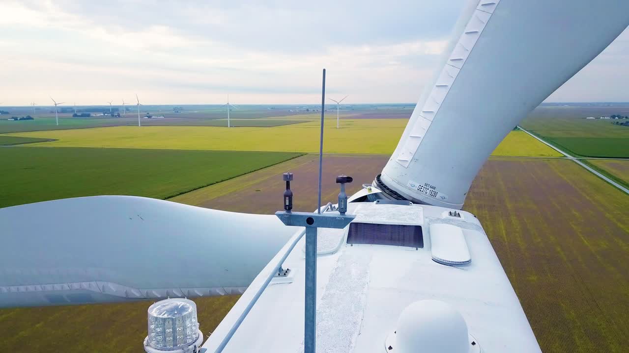 вид с воздуха крупным планом за вращающимися лопастями ветрогенератора и метеорологическим оборудованием на зеленой сельской территории