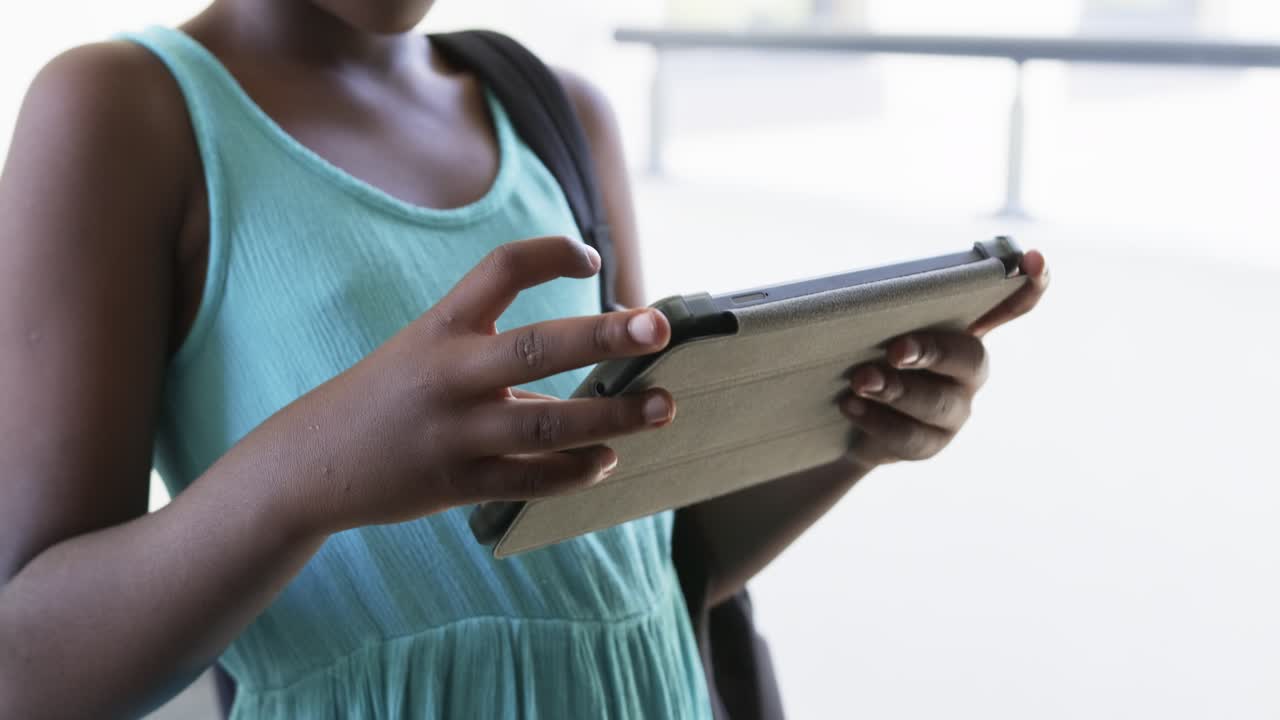 Right index finger is starting taps and swipes while student is steadying tablet in backlit lobby