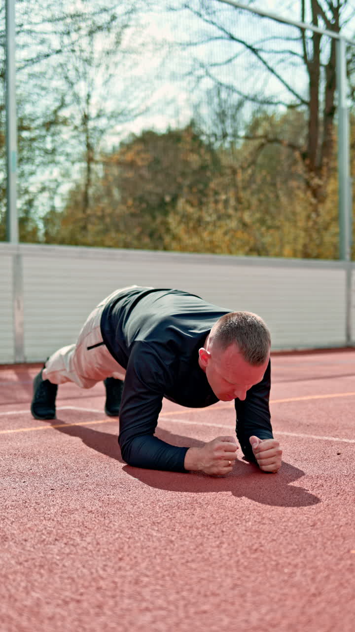 Video di un allenatore sportivo e di un atleta affascinante su un campo sportivo all'aperto. Allenamento all'aperto con uno sfondo cittadino. Allenamento Crossfit.
